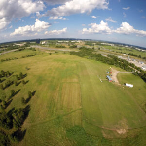 A large field with trees and clouds in the sky.