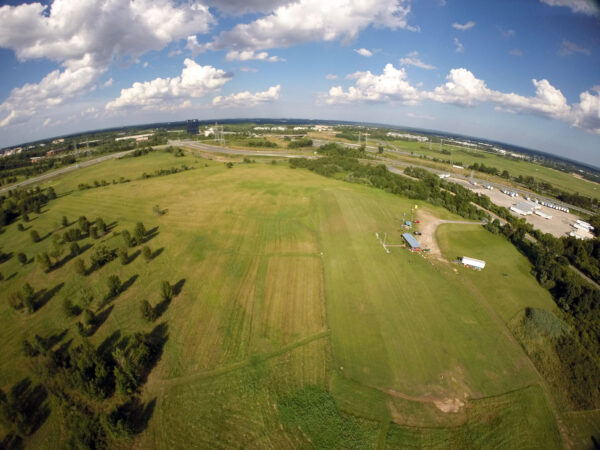 A large field with trees and clouds in the sky.