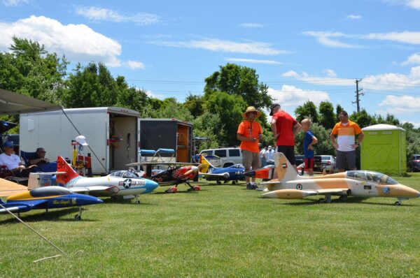 A group of people standing around some small planes.