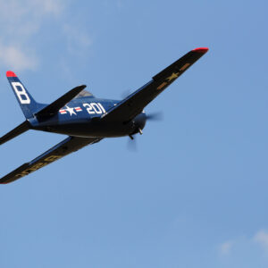 A small airplane flying in the sky with its propeller pointed up.