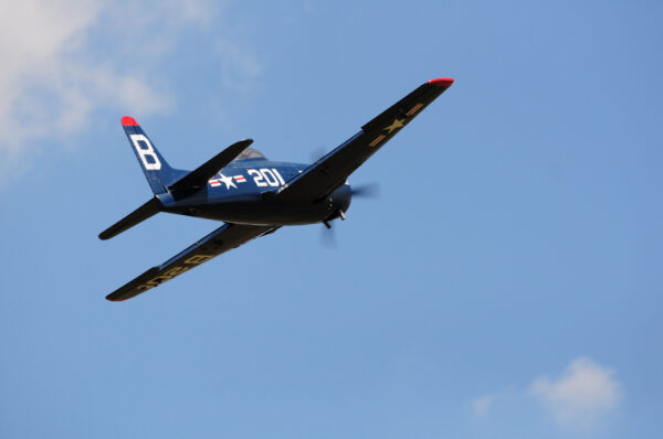 A small airplane flying in the sky with its propeller pointed up.