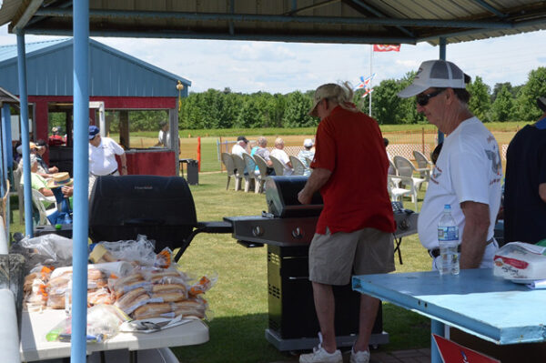 A group of people standing around a grill.